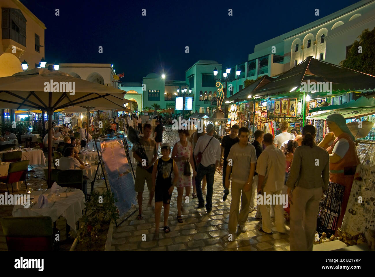 Orizzontale di ampio angolo di turisti a piedi attorno a artigianato tradizionale con bancarelle e negozi all'interno della Medina di notte. Foto Stock
