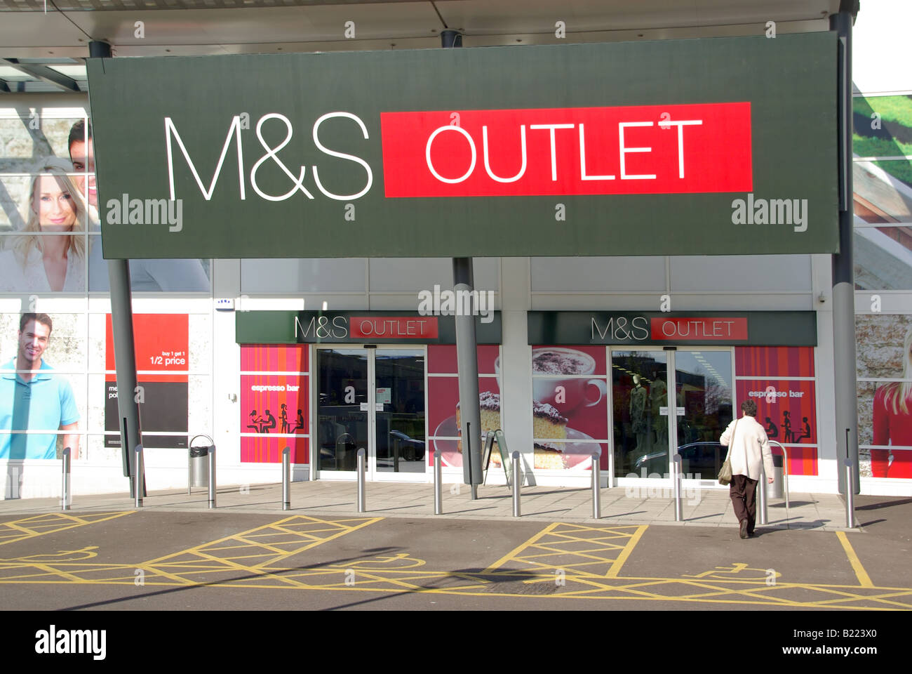 M&S outlet store e logo presso Junction Retail Park, modello con vista posteriore rilasciato, donna che acquista in procinto di entrare nel negozio a Thurrock Essex Inghilterra, Regno Unito Foto Stock