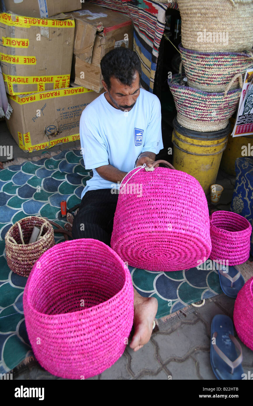 Uomo locale maniglie di cucitura su cestelli rosa pronti a vendere al souk di Marrakech Foto Stock