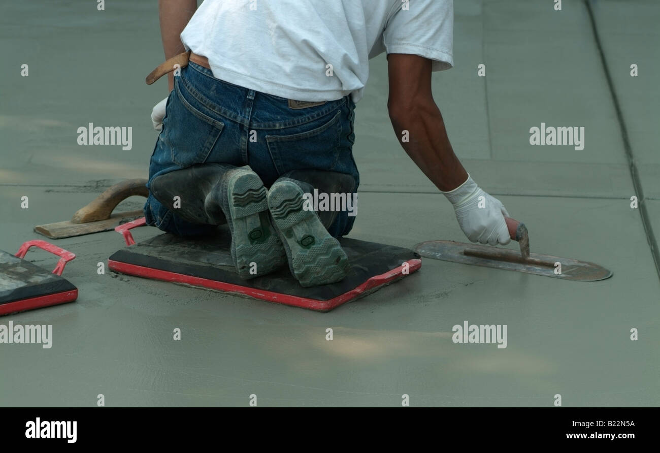 Workman livellamento di calcestruzzo bagnato con un Darby durante la costruzione di una strada di fronte a una casa privata in California. Foto Stock