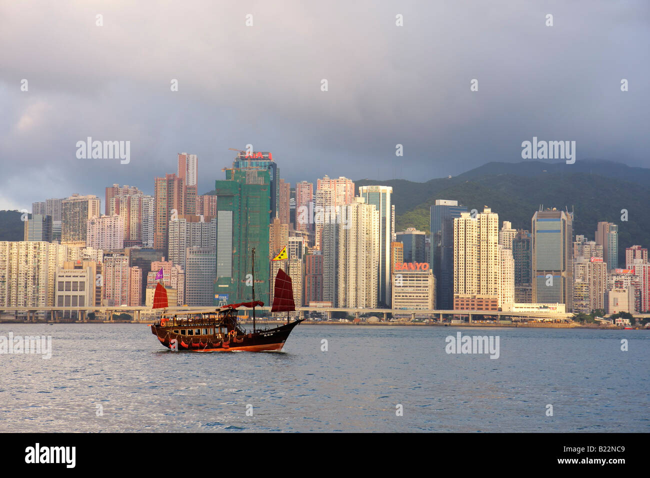 Junk nave con l'Isola di Hong Kong skyline in background visto dalla penisola di Kowloon Foto Stock