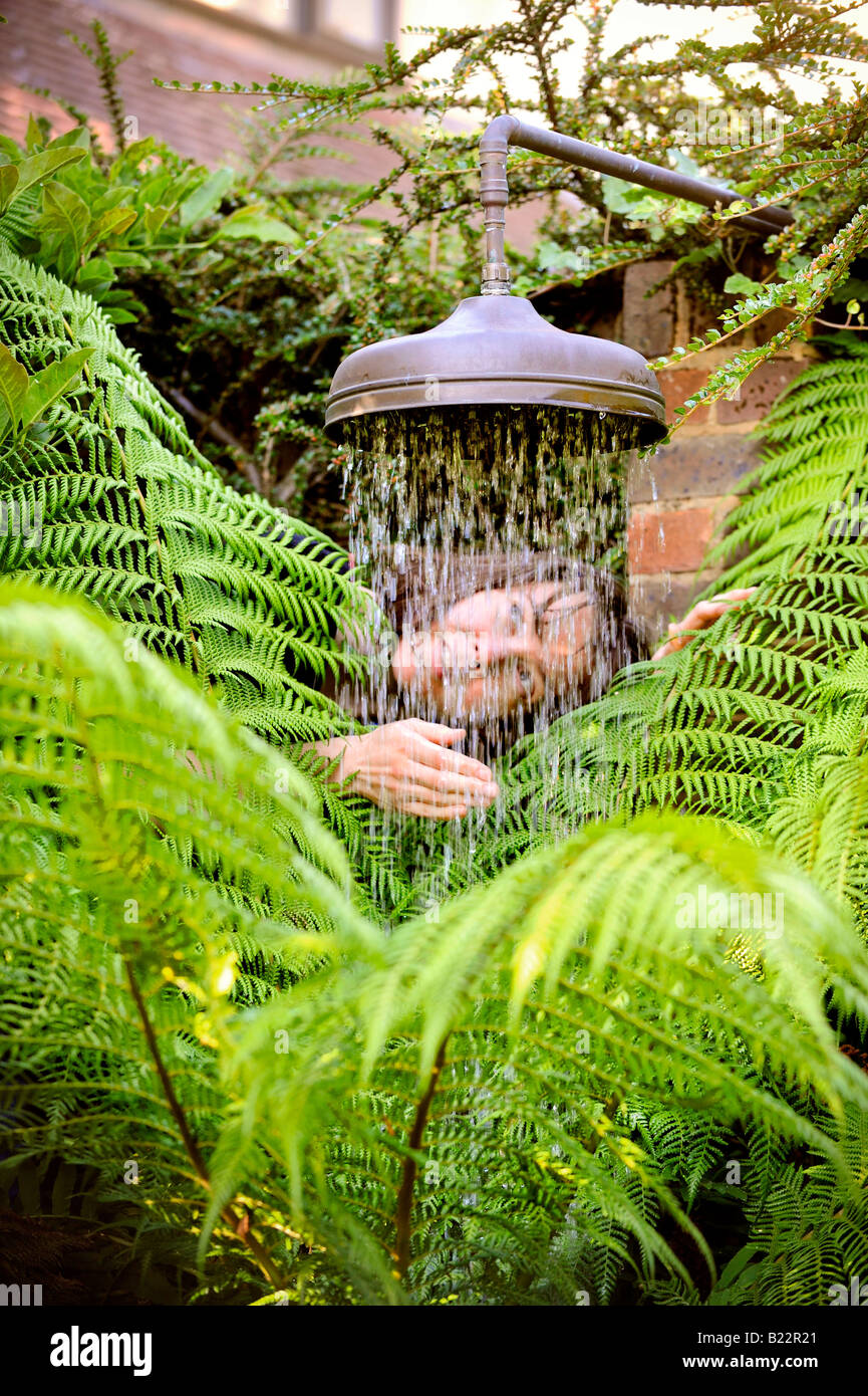 Un appassionato di giardinaggio con una doccia rigenerati testa essendo utilizzato per le piante di acqua. Foto da Jim Holden. Foto Stock