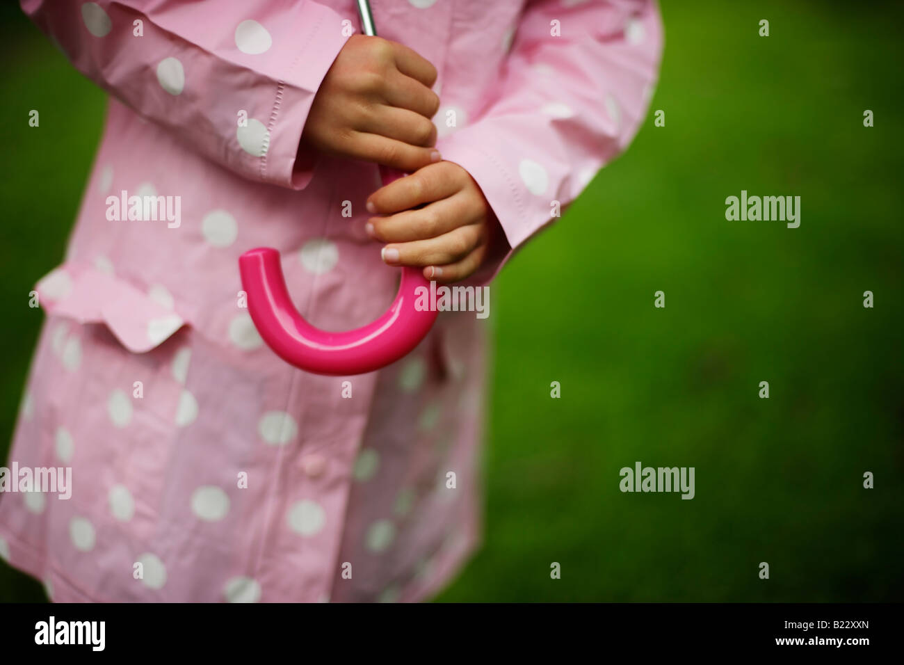 Bambina di cinque anni si trova in giardino con ombrellone in un giorno di pioggia Foto Stock
