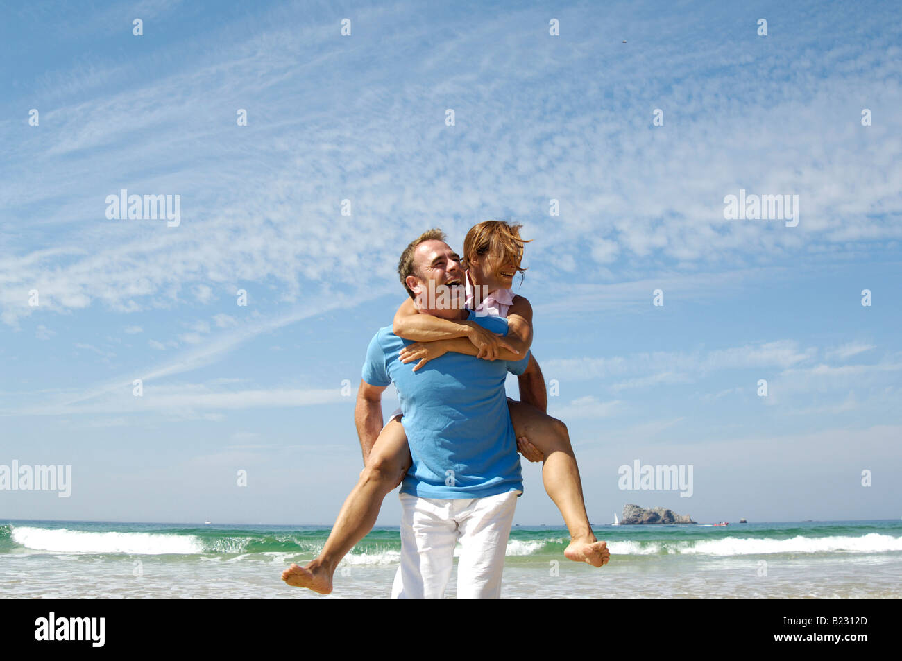 Piggybacking uomo donna sulla spiaggia Foto Stock