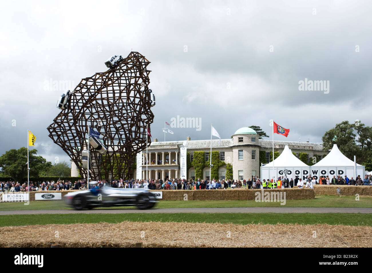 Goodwood House e Landrover display centrale con auto da corsa in movimento in primo piano, Goodwood Festival della velocità 2008 Foto Stock