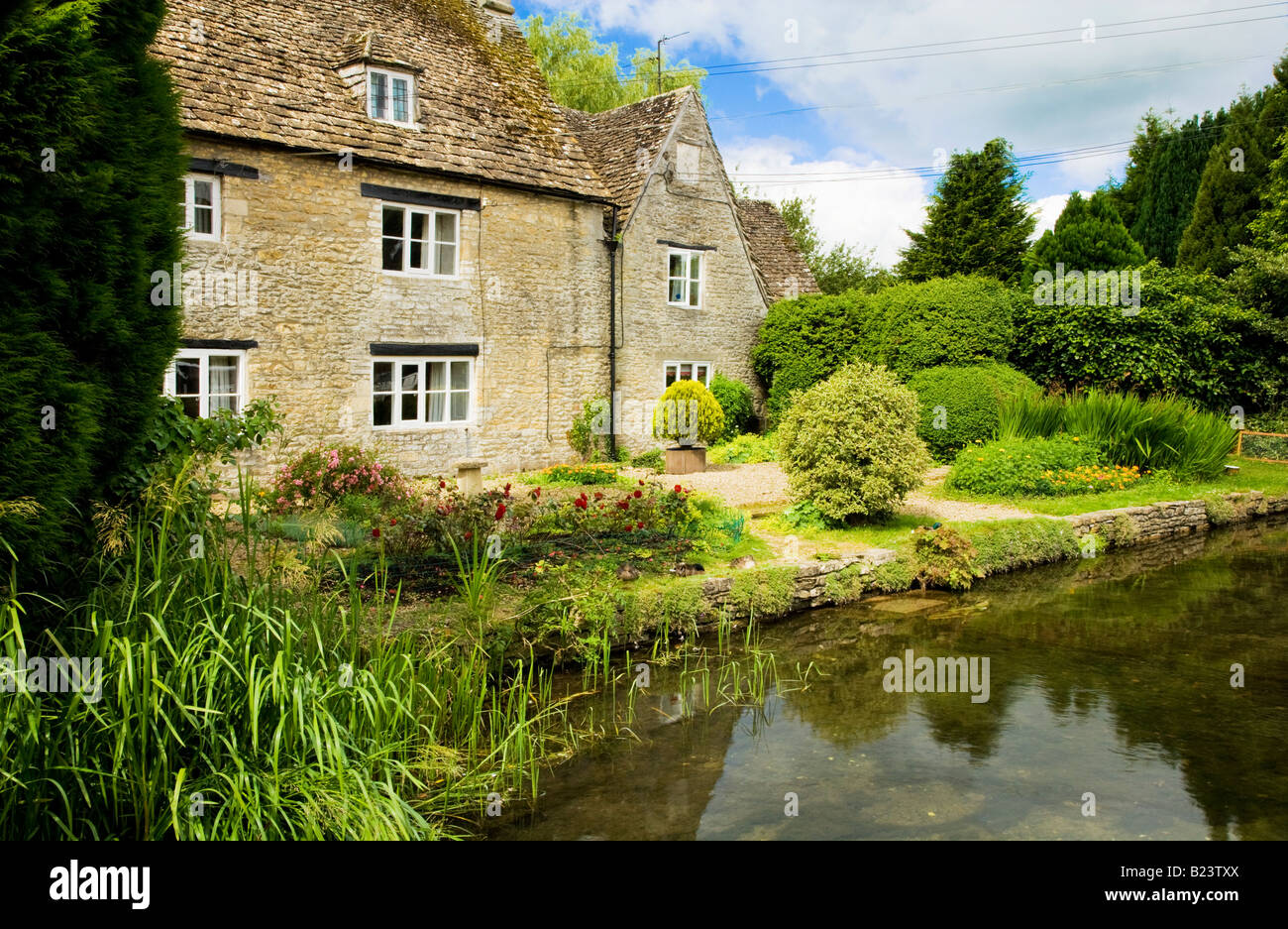 Il Tamigi che fluisce oltre a Cotswold casa di pietra in villaggio di Ashton Keynes, Wiltshire, Inghilterra, Regno Unito Foto Stock
