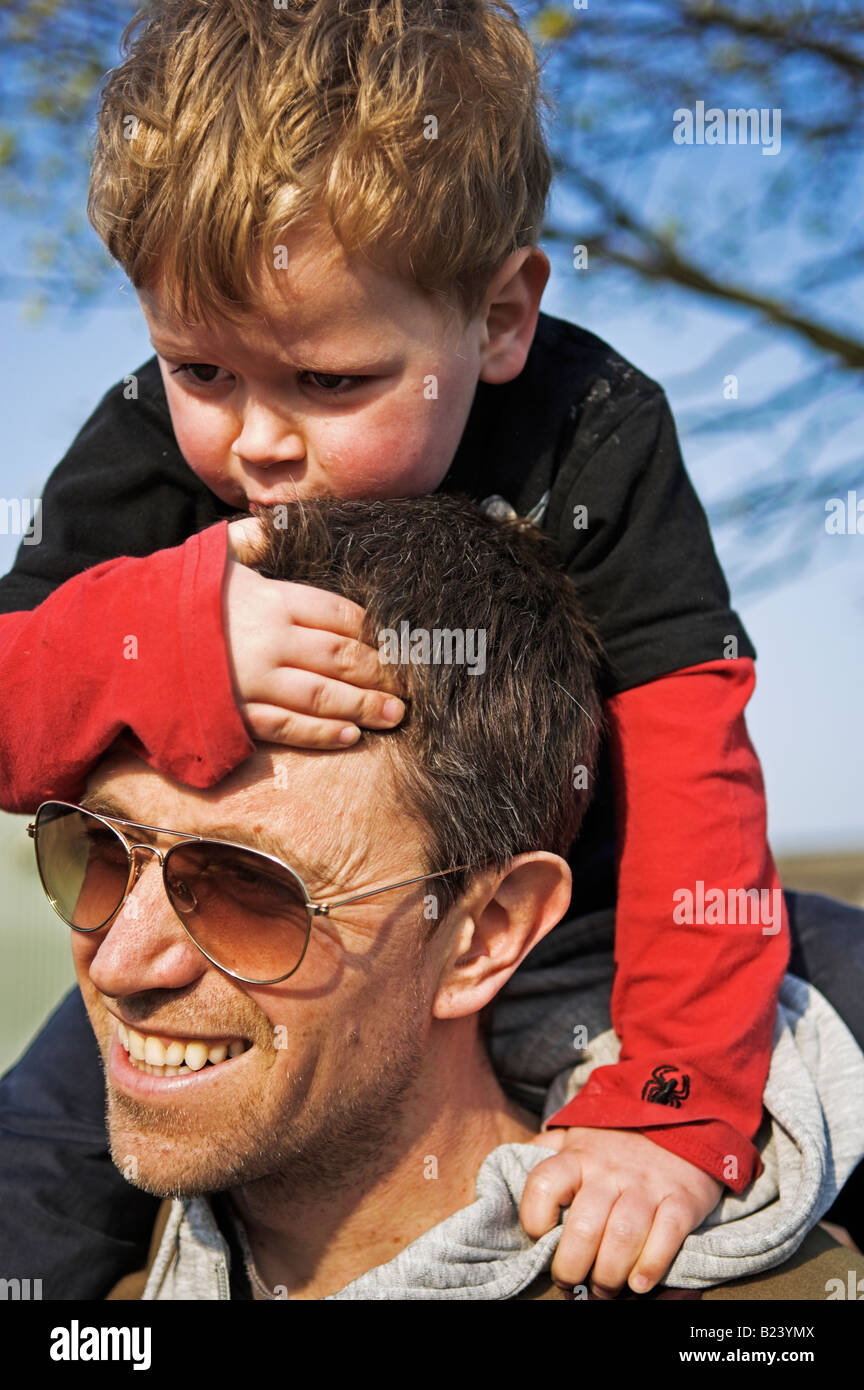 Padre che trasportano preoccupati figlio 4 5 piggyback su spalle Foto Stock