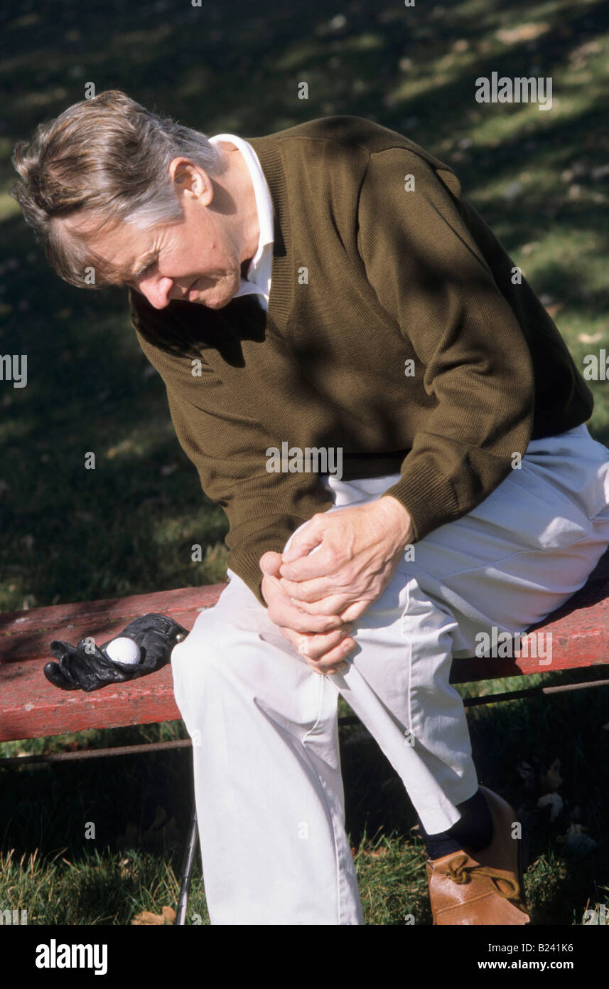 SENIOR uomo sperimenta il dolore al ginocchio SUL CAMPO DA GOLF Foto Stock