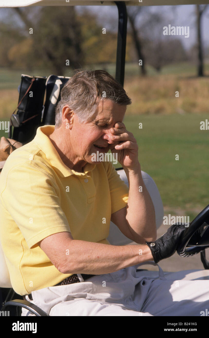 SENIOR uomo con mal di testa seduto in golf cart Foto Stock