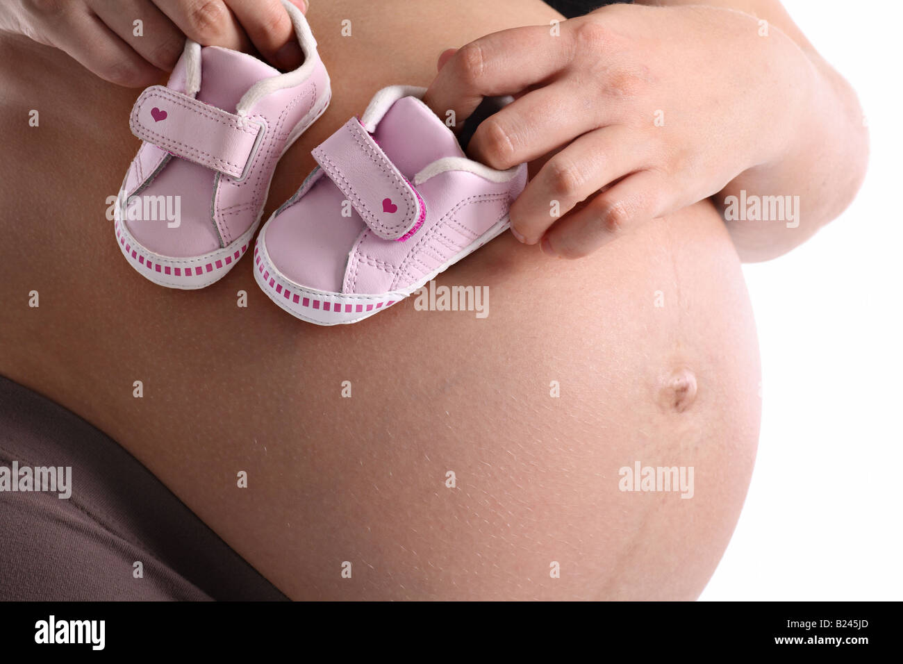 Donna incinta con il piccolo bambino scarpe sul suo ventre Foto Stock