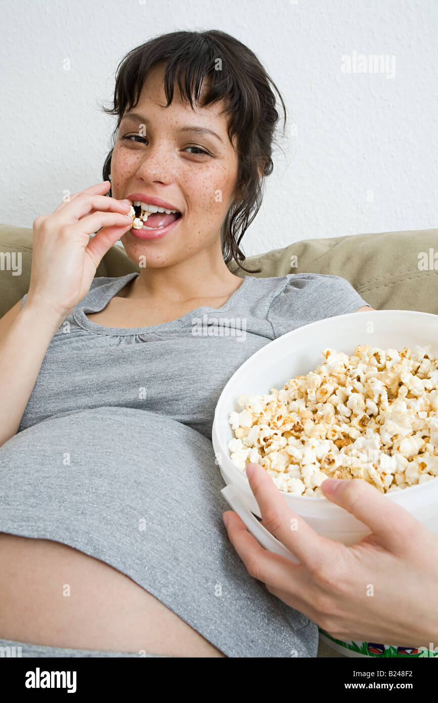 Donna incinta mangiare popcorn Foto Stock
