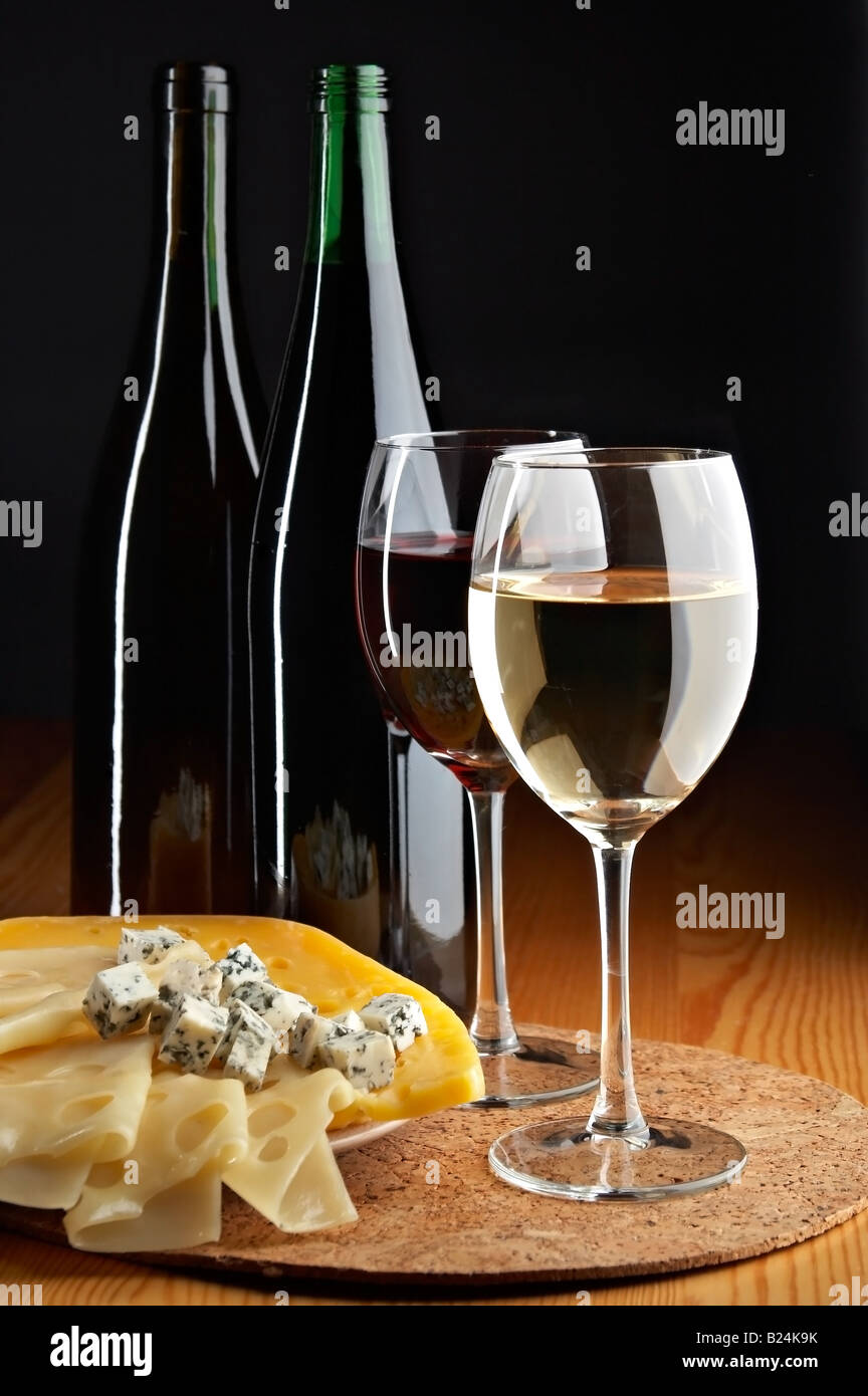 Ancora vita con formaggio vini rossi e bianchi su sfondo nero Foto Stock