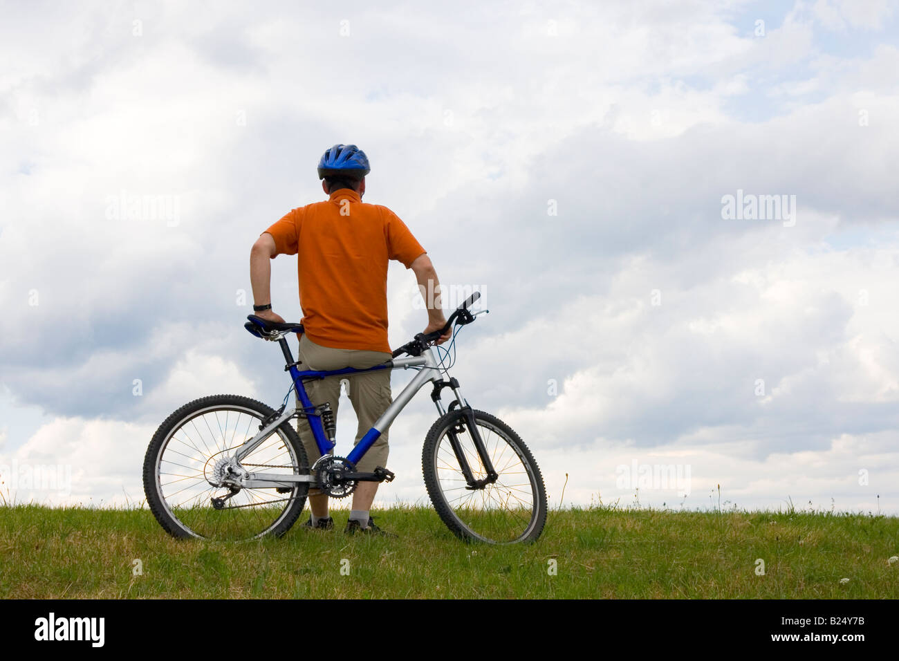 Uomo in piedi con la sua mountain bike in un prato Foto Stock