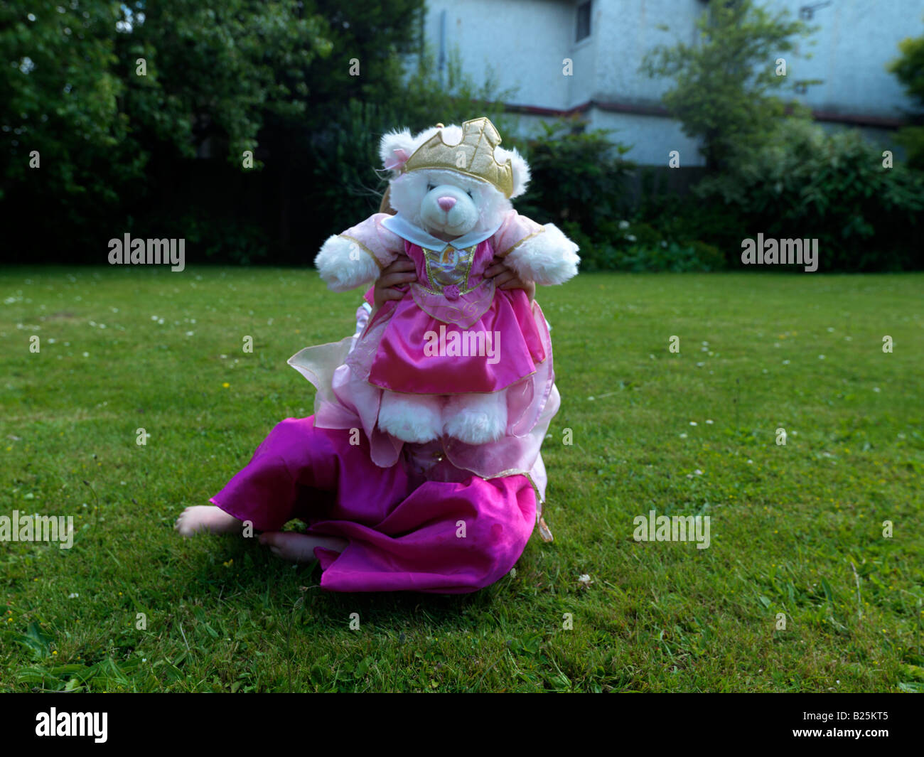 Ragazza vestita come principessa con un orso principessa dentro Un Surrey Giardino Inghilterra Foto Stock