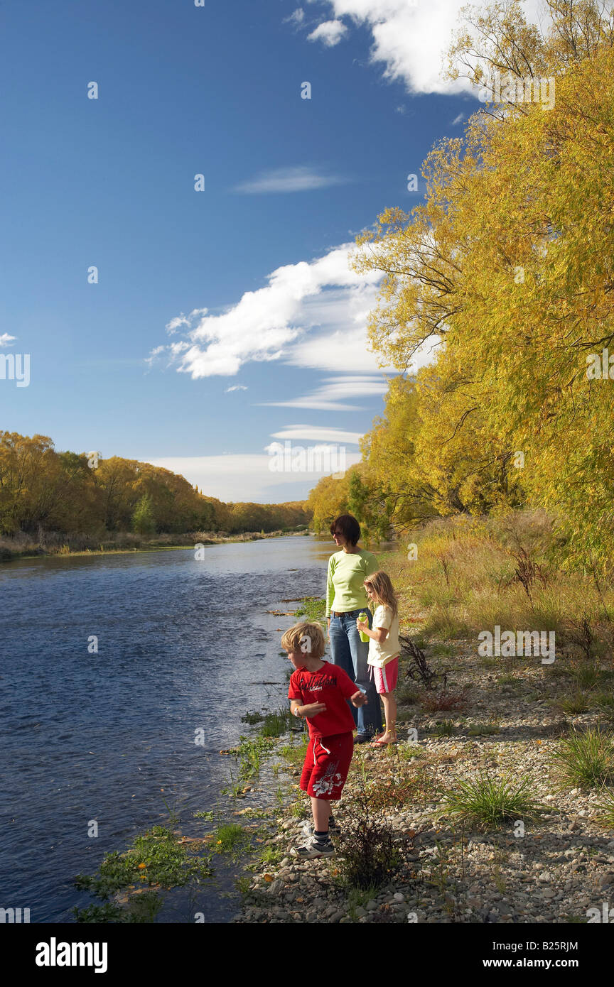 La famiglia che lanciano pietre Manuherikia Fiume e alberi d'Autunno Alexandra Central Otago Isola del Sud della Nuova Zelanda Foto Stock