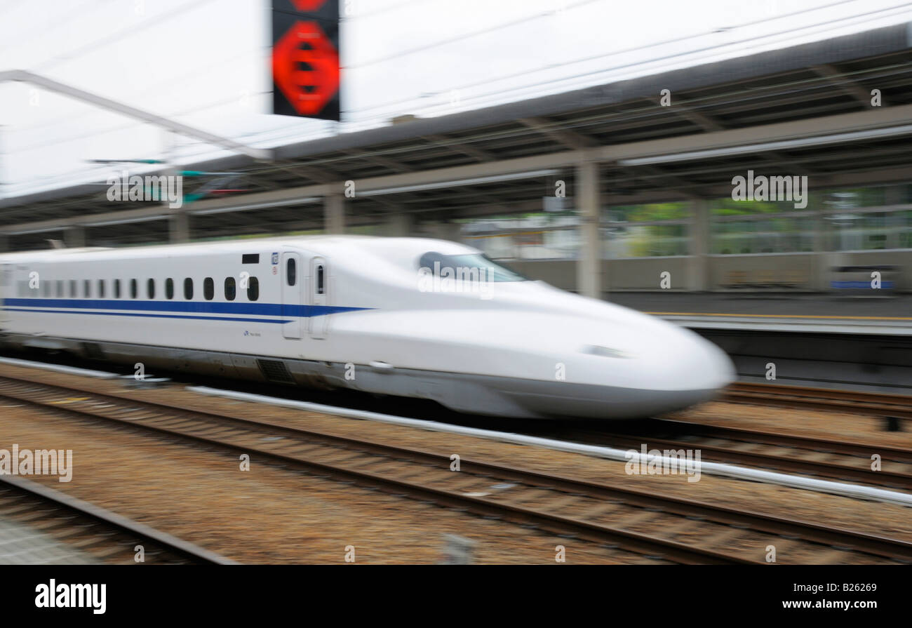 Un treno proiettile giapponese (Shinkansen) che passa attraverso una stazione ferroviaria Foto Stock