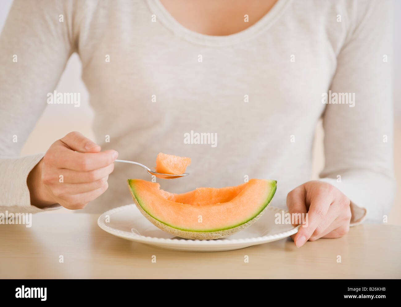 Donna di mangiare il melone cuneo Foto Stock