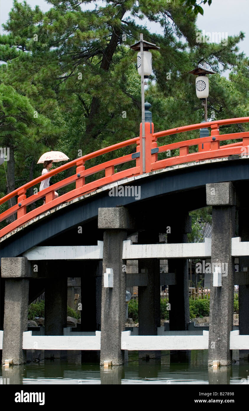 Persona che attraversa la famosa vermiglio ponte arcuato chiamato Taikobashi al Sumiyoshi Taisha in Osaka Foto Stock