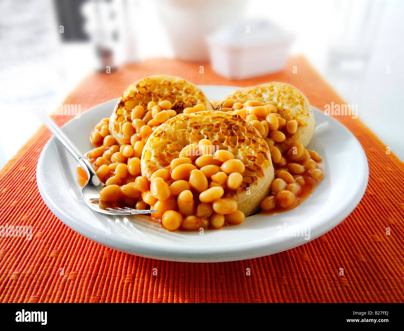 Fagioli al forno su cialdine servito come un pasto su una piastra bianca in una tabella Foto Stock