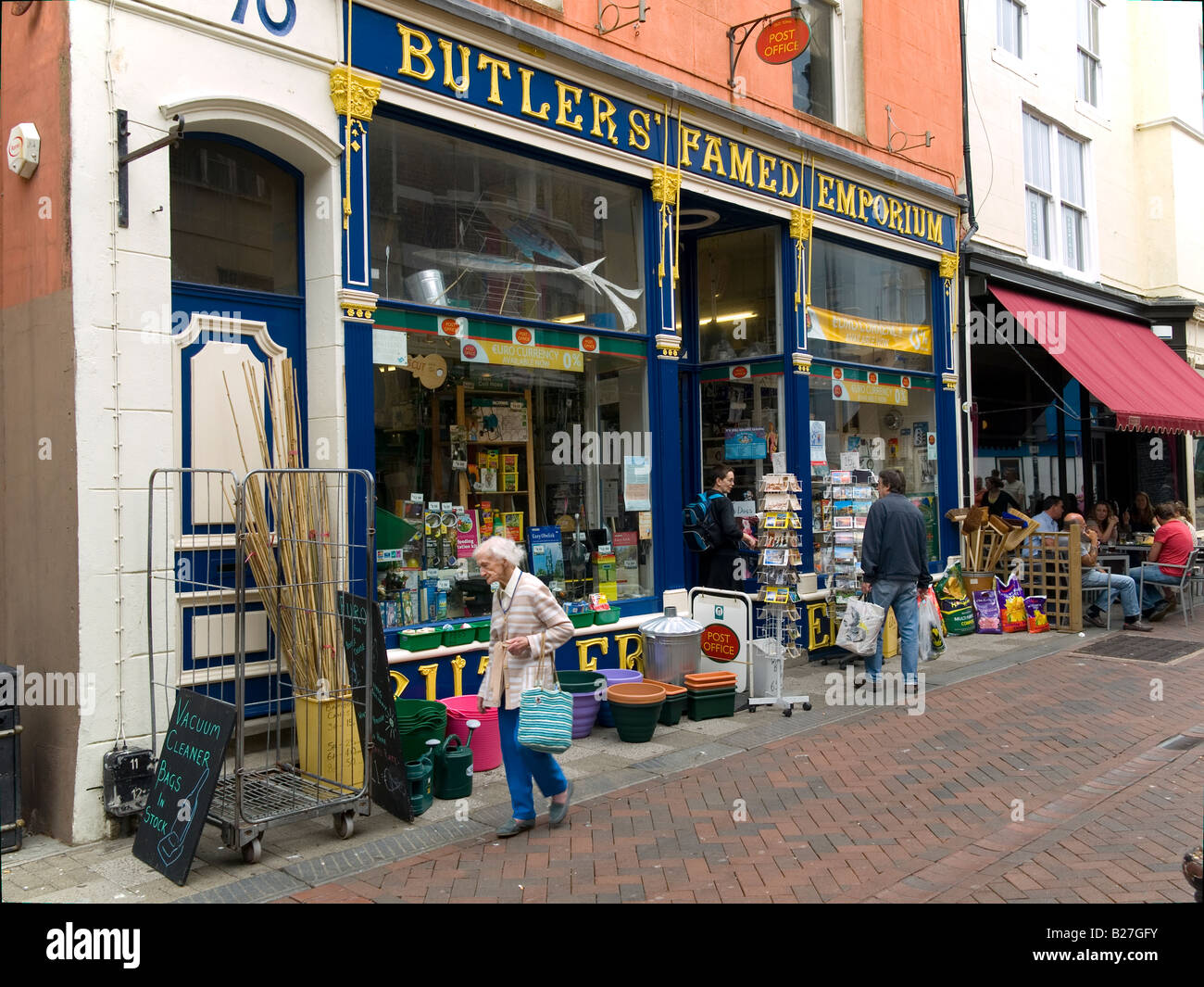 Una vecchia signora cammina passato maggiordomi Famed Emporium un magazzino generale e Ufficio postale in Hastings Old Town SUSSEX REGNO UNITO Foto Stock