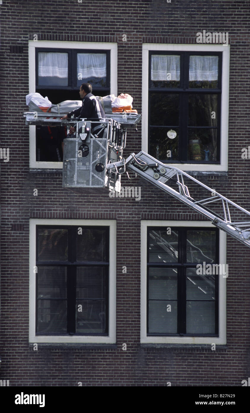 Uomo malato di essere evacuato dal fuoco departement dovuta a strette scalinate nel vecchio edificio. Amsterdam, Paesi Bassi. Foto Stock