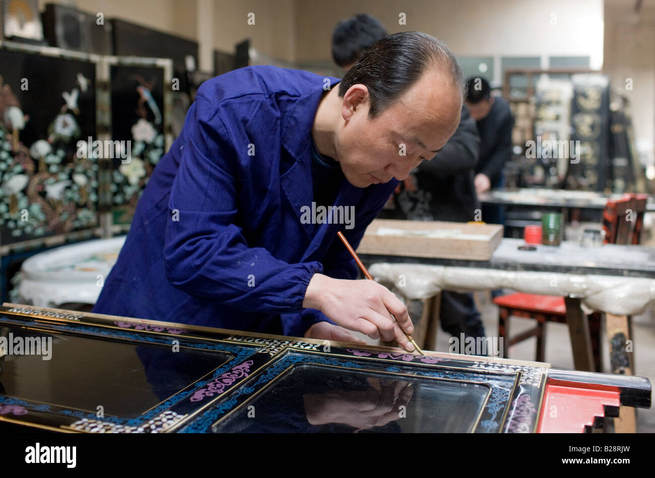 Intarsio artigiano al lavoro sul fuoco di lacca schermo al negozio di souvenir e una fabbrica di mobili Xian Cina Foto Stock