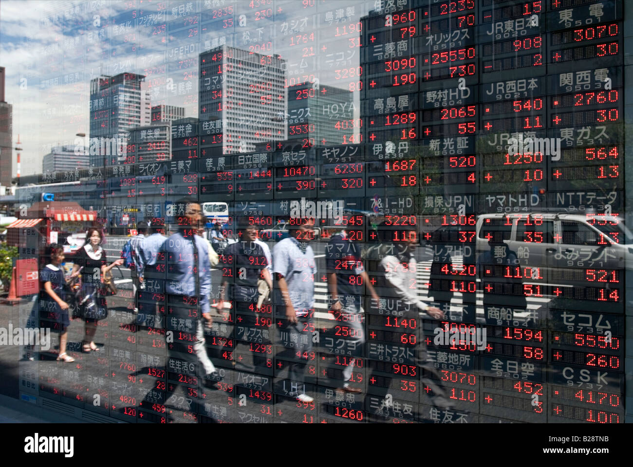 Imprenditori riflessa nella finestra di Tokyo società di titoli mobiliari che visualizza le ultime del mercato azionario figure di exchange Foto Stock