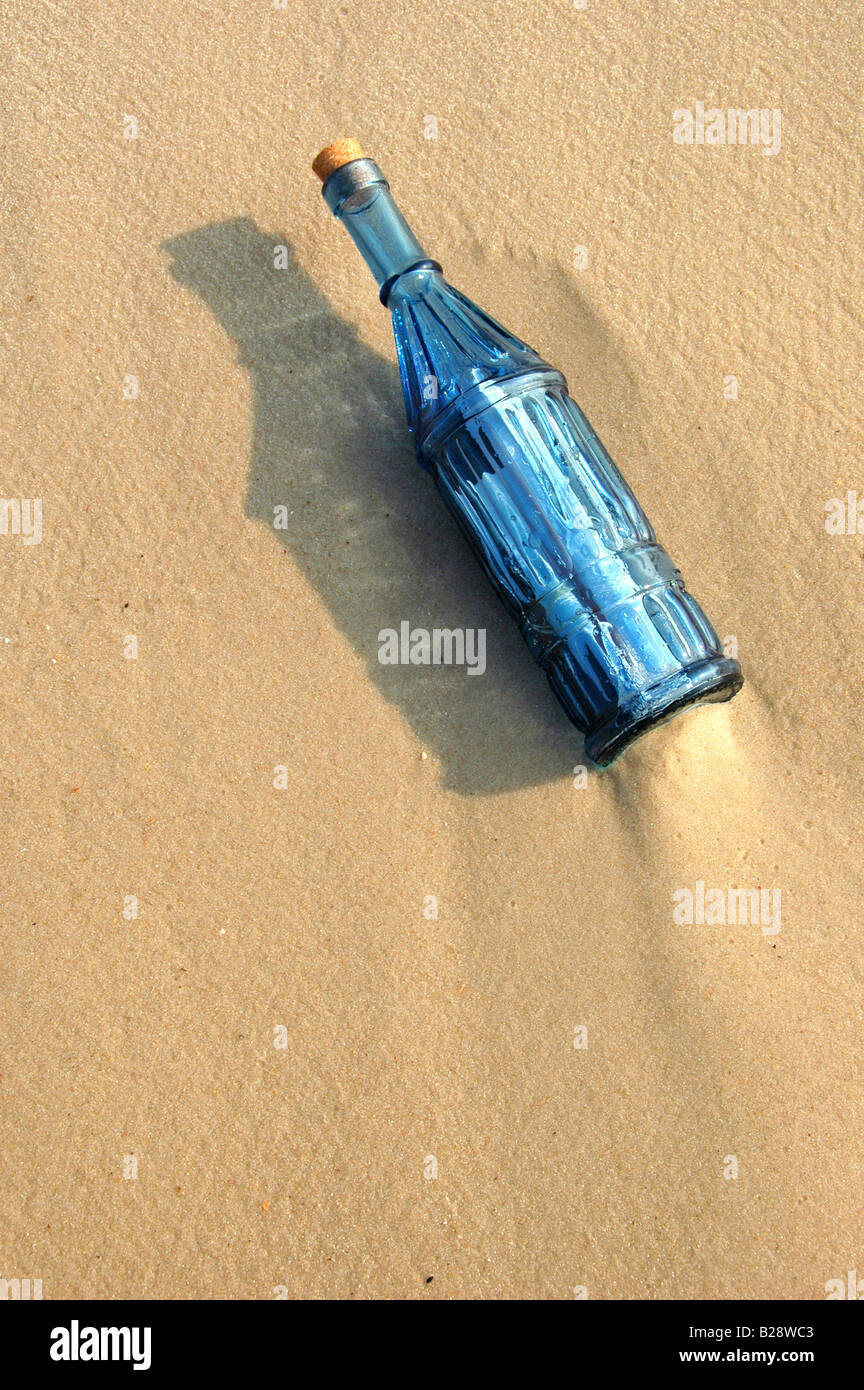 Un messaggio in bottiglia in un'annata bottiglia blu sulla sabbia Foto Stock
