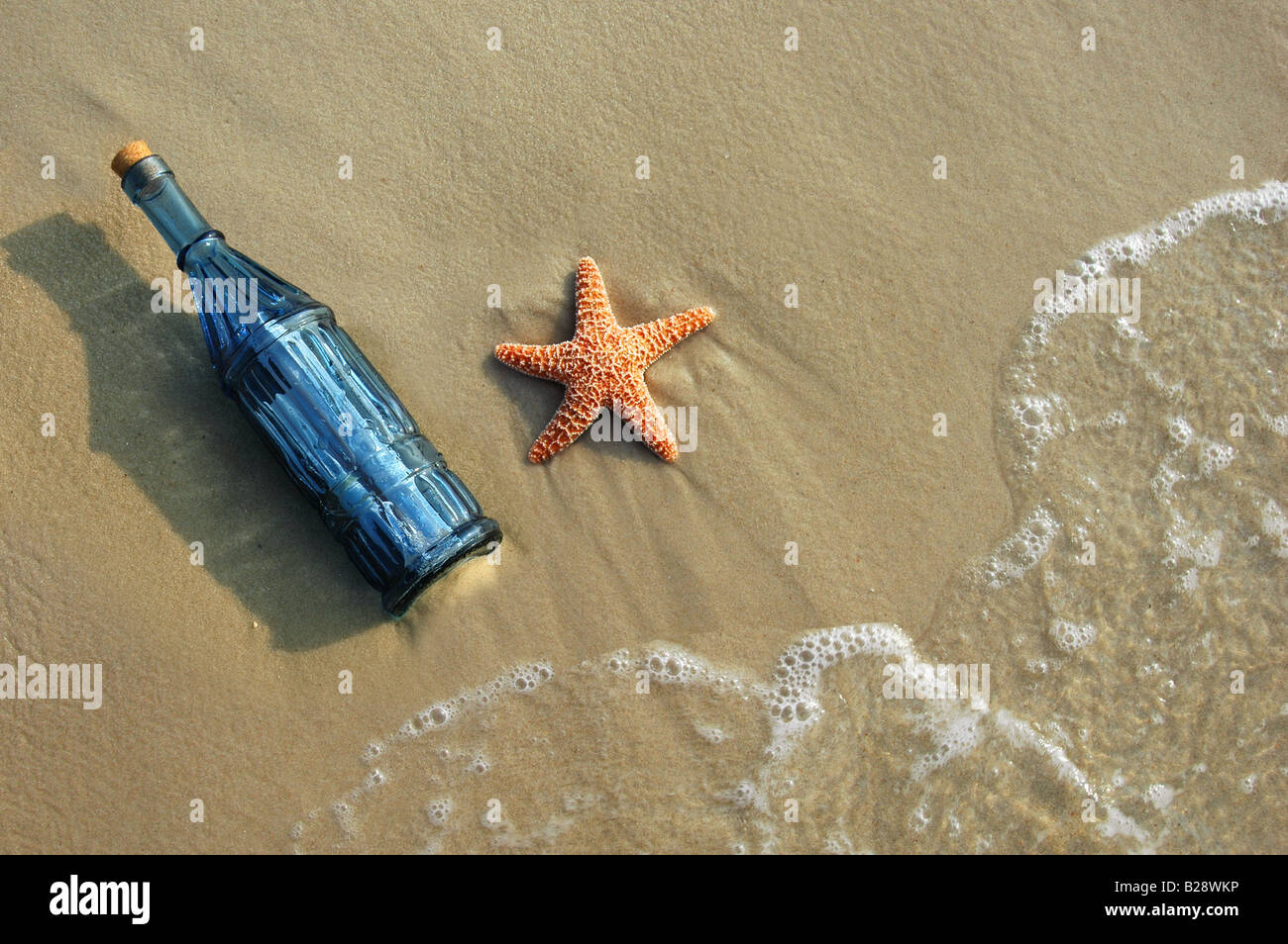 Vintage un messaggio in bottiglia e stelle marine su una riva sabbiosa Foto Stock