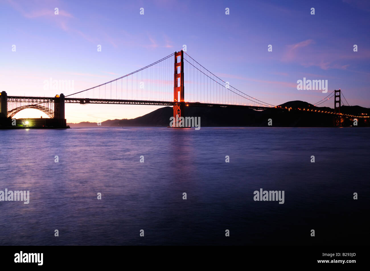 Torre Sud del Golden Gate Bridge si accende contro il bellissimo tramonto Cielo con Fort Point illuminata da proiettori fluorescenti Foto Stock