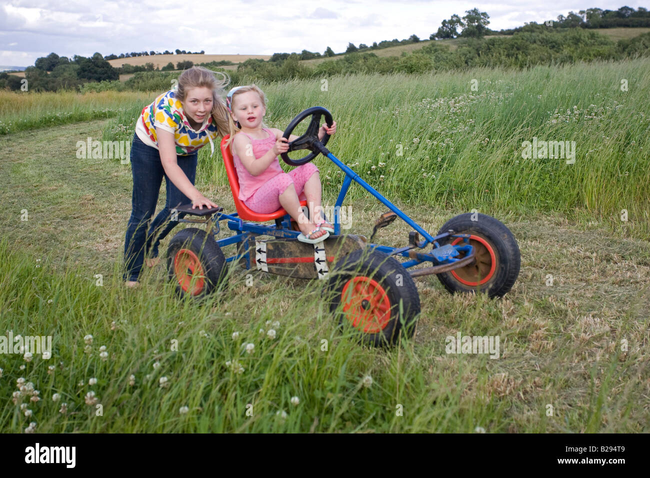 Bambini divertirsi sul pedale go cart nel campo di fattoria di Cotswolds REGNO UNITO Foto Stock