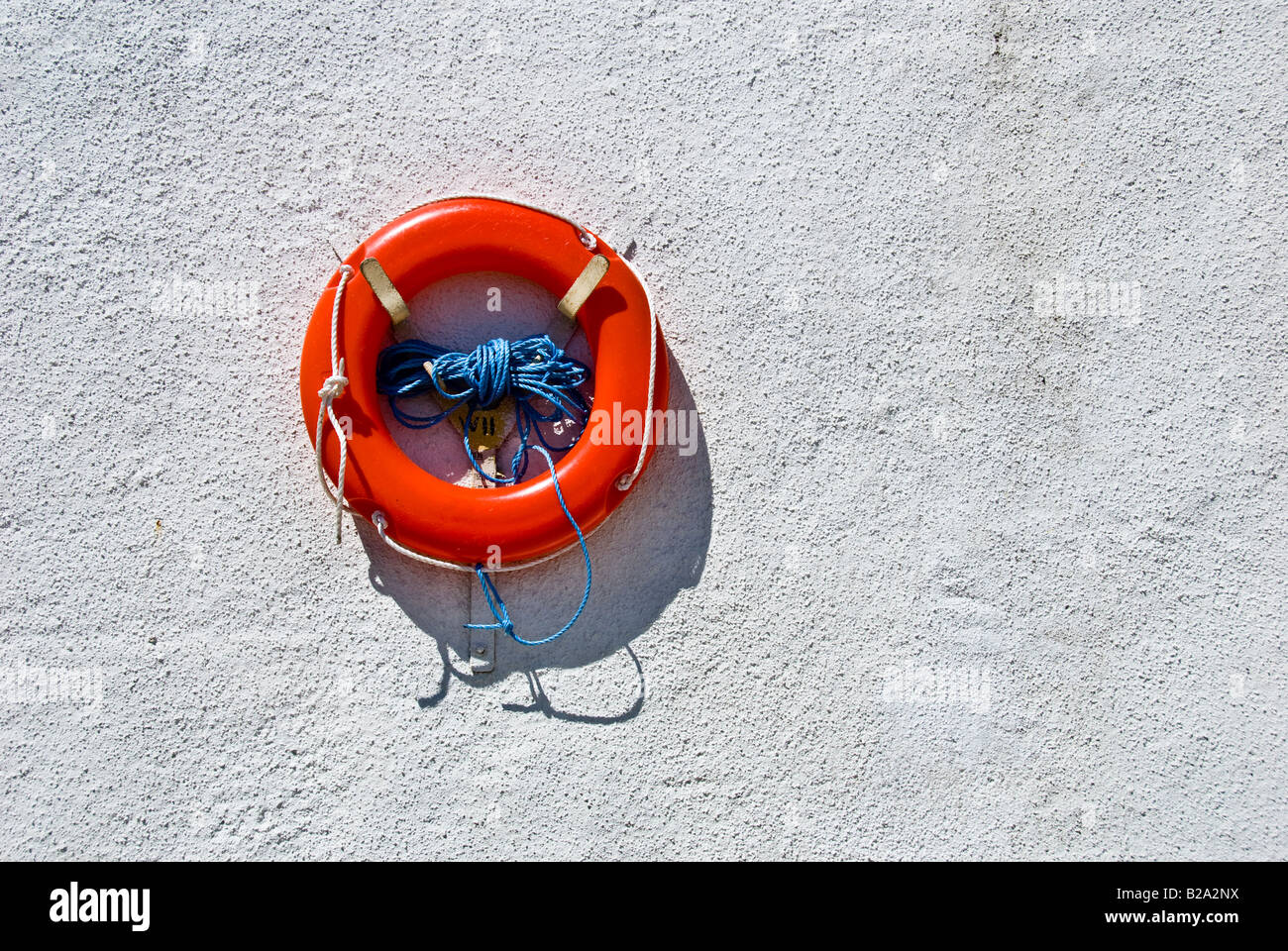 Vita arancione nastro e corda blu su una parete bianca. Foto Stock