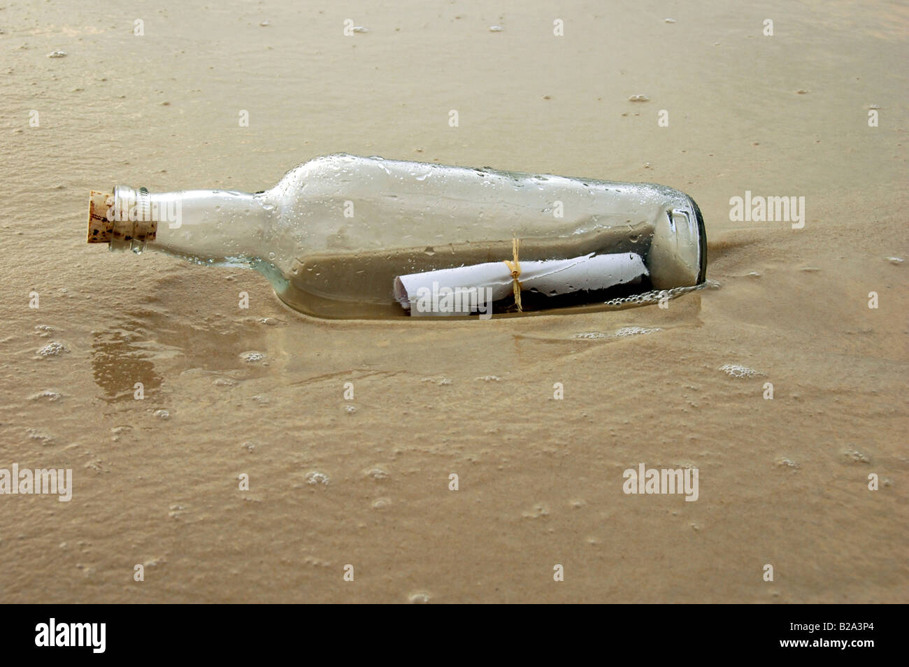 Vecchia bottiglia con il messaggio sulla riva della spiaggia Foto Stock