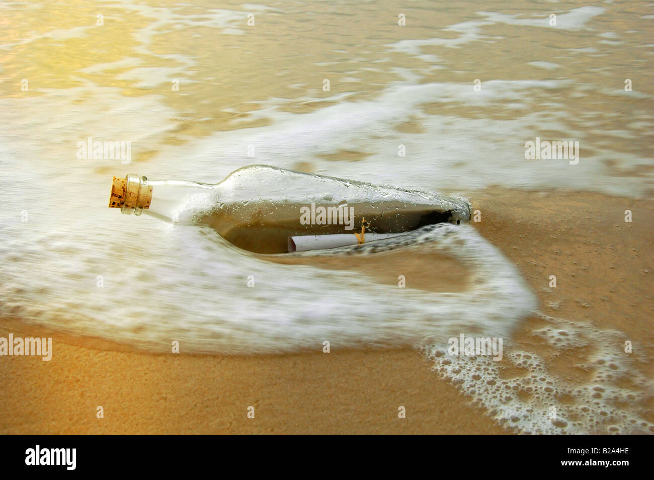 Bottiglia con messaggio lavato a riva dalle onde al tramonto Foto Stock