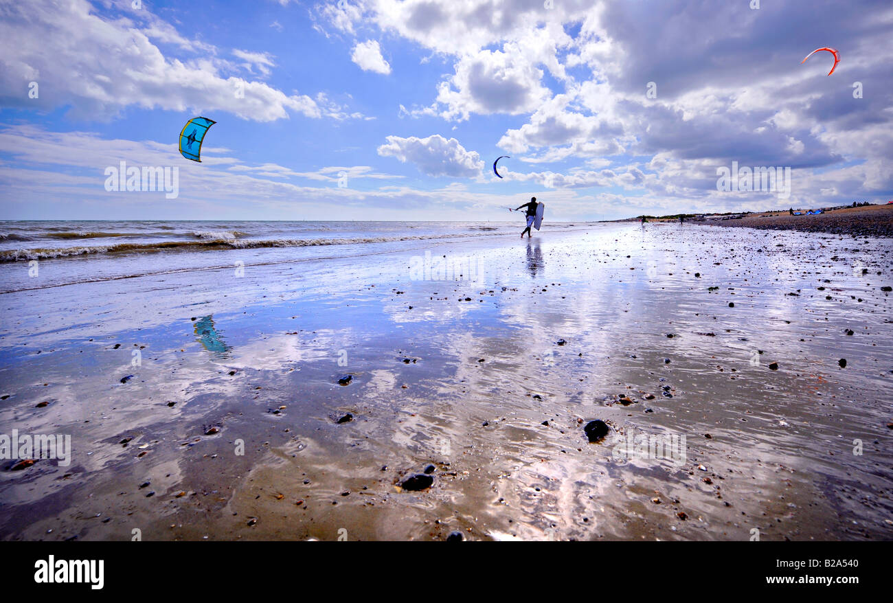 Kite surfer in esecuzione sul bagnato spiaggia sabbiosa stagliano contro il cielo. Foto da Jim Holden. Foto Stock