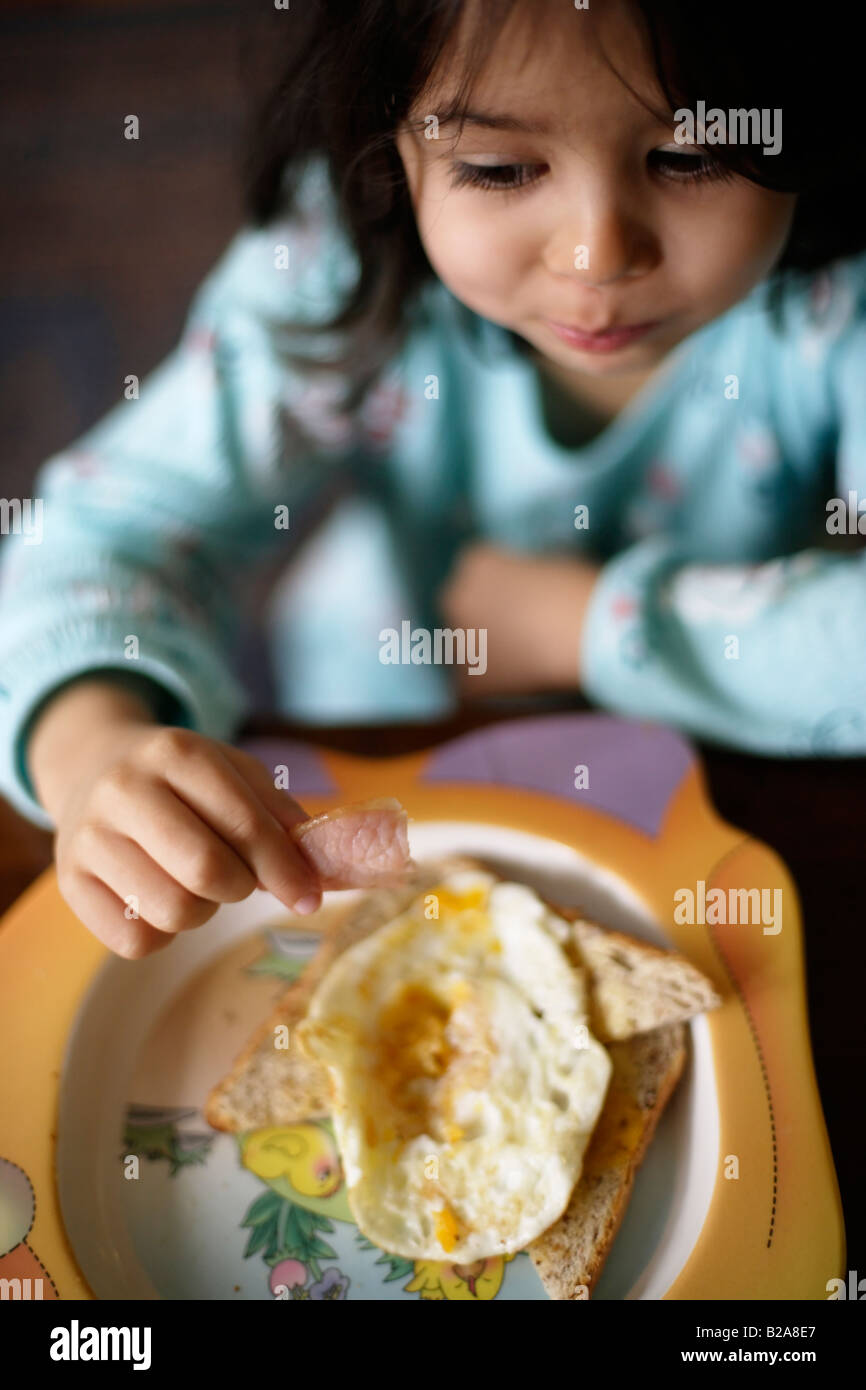 Ragazza di età compresa tra i cinque mangia colazione fritta Foto Stock