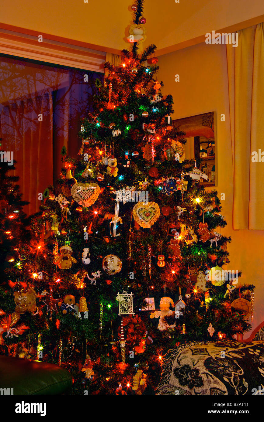 Illuminato di albero di Natale artificiale caricato con luci colorate home  creato ornamenti e decorazioni in un angolo salotto Foto stock - Alamy