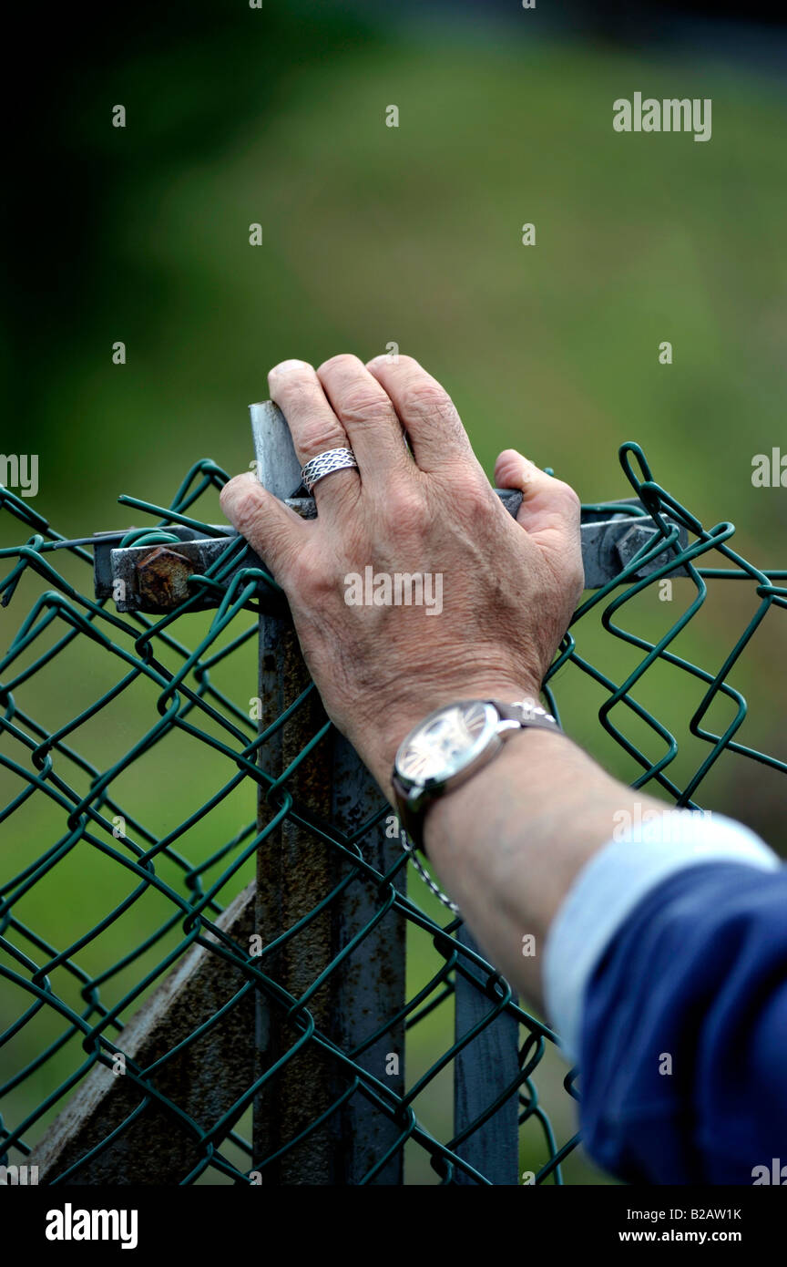 Man mano con anello di nozze in appoggio sulla ruggine catena collegamento recinto Foto Stock