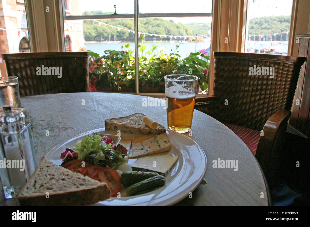 Un tradizionale pranzo inglese di plowman e una pinta di birra nel pub King of Prussia sul lungomare di Fowey, Cornovaglia, Inghilterra, Regno Unito Foto Stock