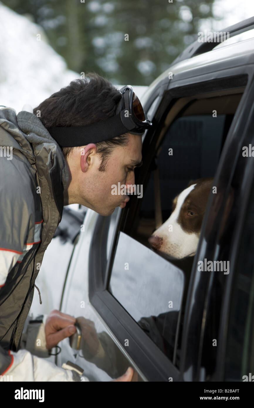 Giovane uomo affettuoso al cane attraverso la finestra SUV Foto Stock