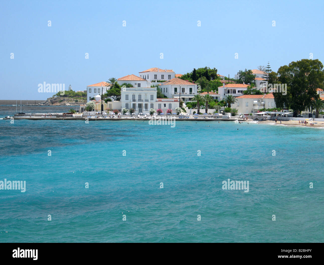 Una parte di Spetses cittadina dell'isola Grecia case tradizionali di una piccola spiaggia ed un faro può essere visto Foto Stock