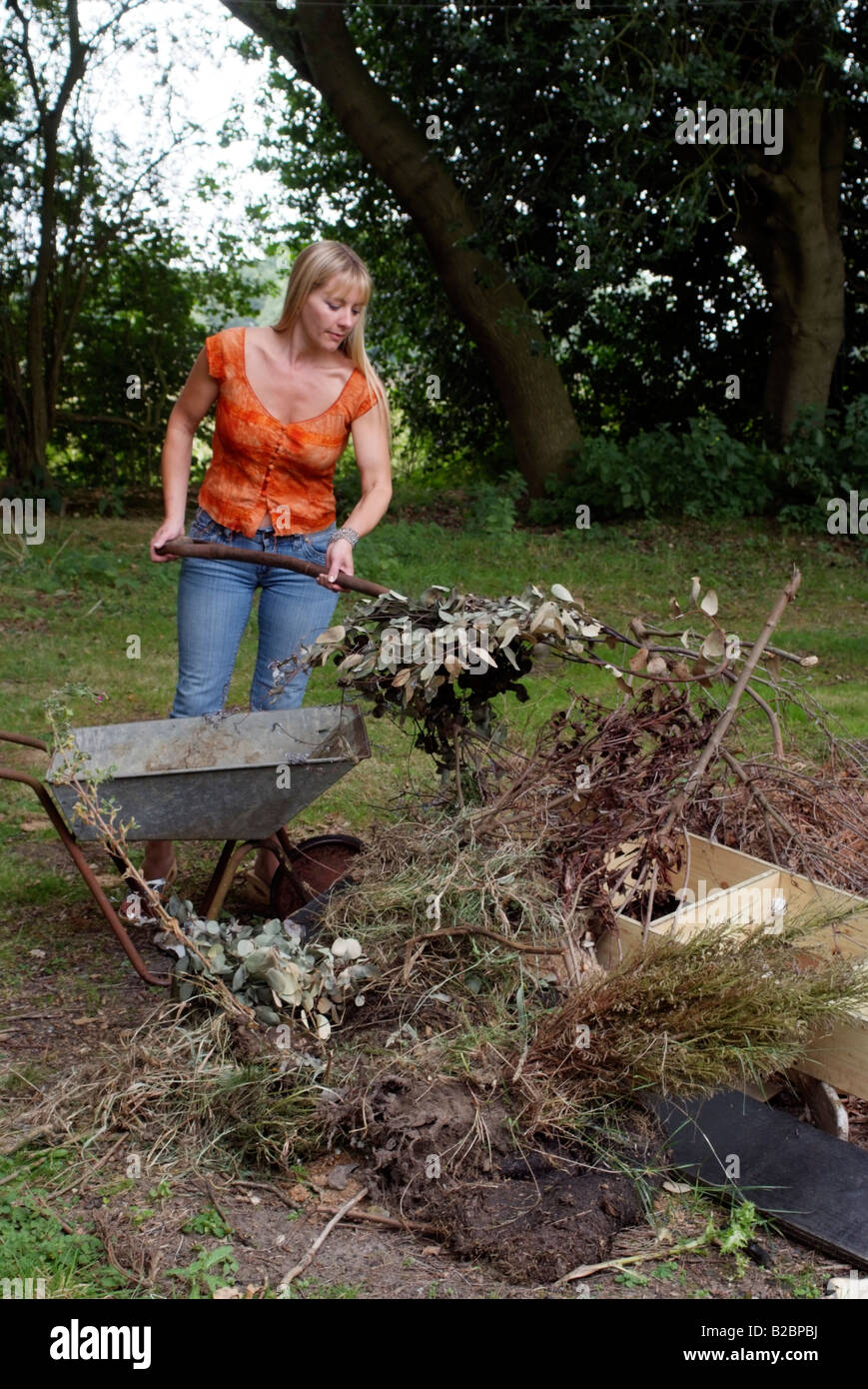Garden clean up donna spazzatura in movimento su una catasta Foto Stock