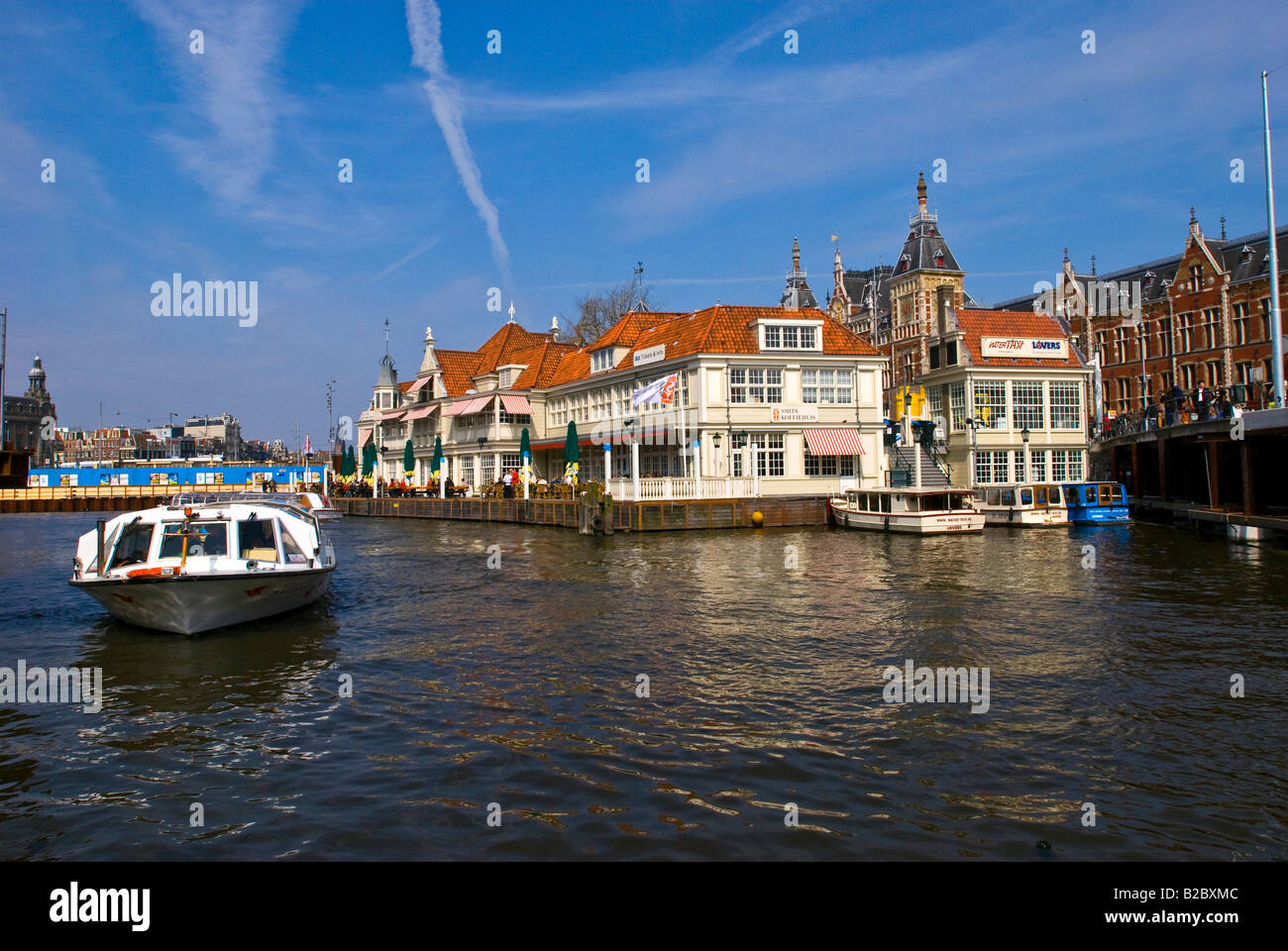 La stazione ferroviaria e la piazza della stazione, Stationsplein, con il porto e gli edifici per le vie navigabili interne, Amsterdam, Olanda Foto Stock