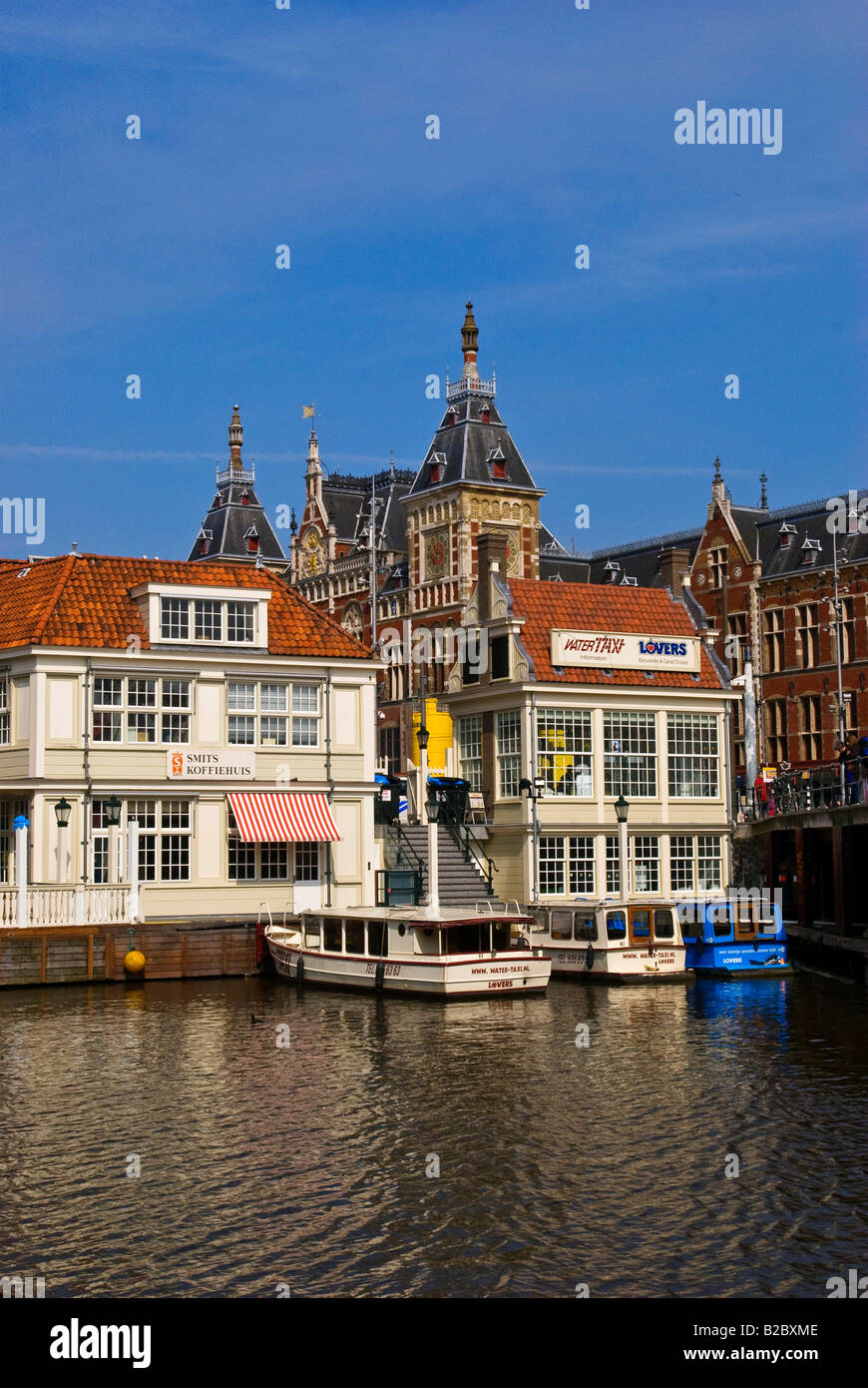 La stazione ferroviaria e la piazza della stazione, Stationsplein, con il porto e gli edifici per le vie navigabili interne, Amsterdam, Olanda Foto Stock