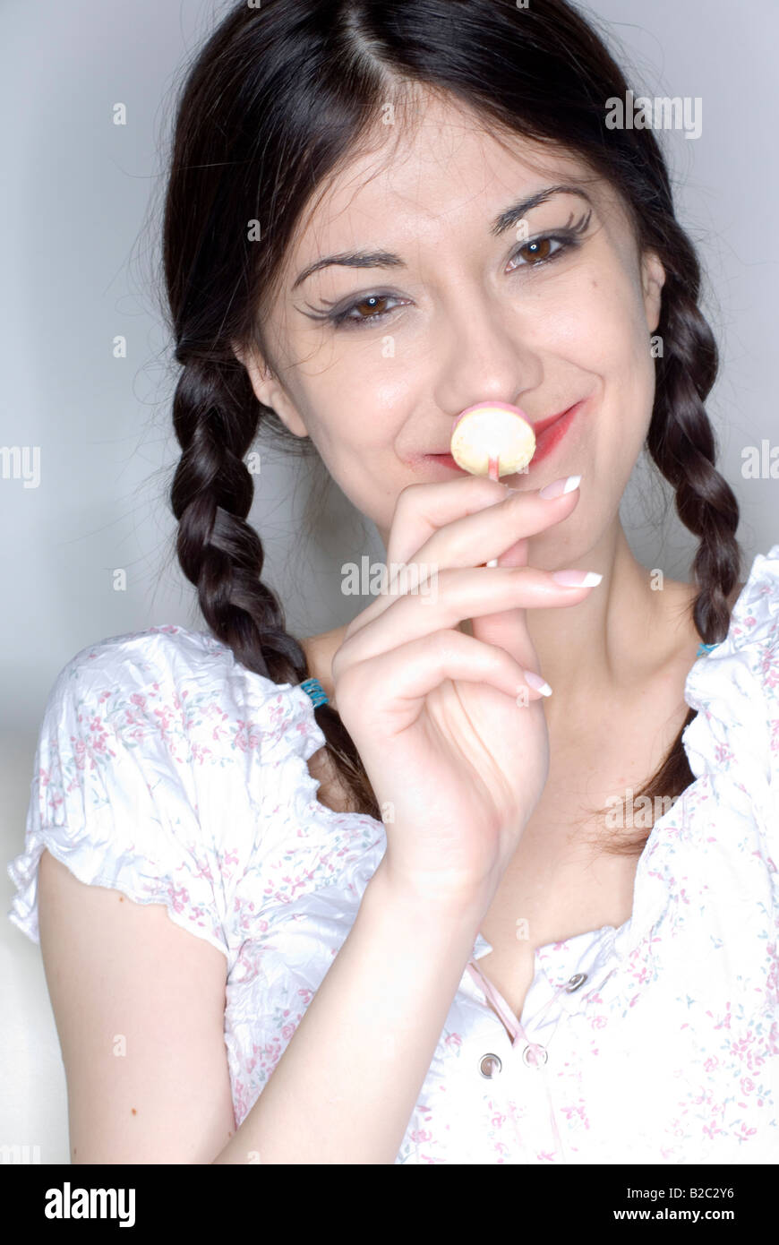 Giovane donna con due trecce e per lecca-lecca Foto Stock