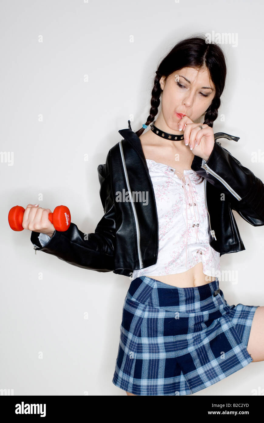 Giovane donna con due trecce, tenendo un barbell e una per lecca-lecca Foto Stock