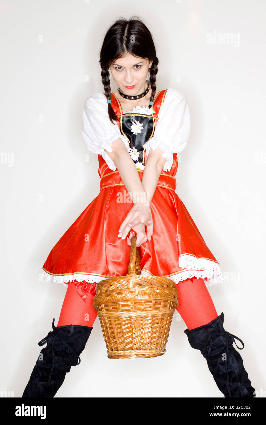 Giovane donna con due trecce che indossa un vestito con grembiule e jackboots, tenendo in mano un cestello Foto Stock