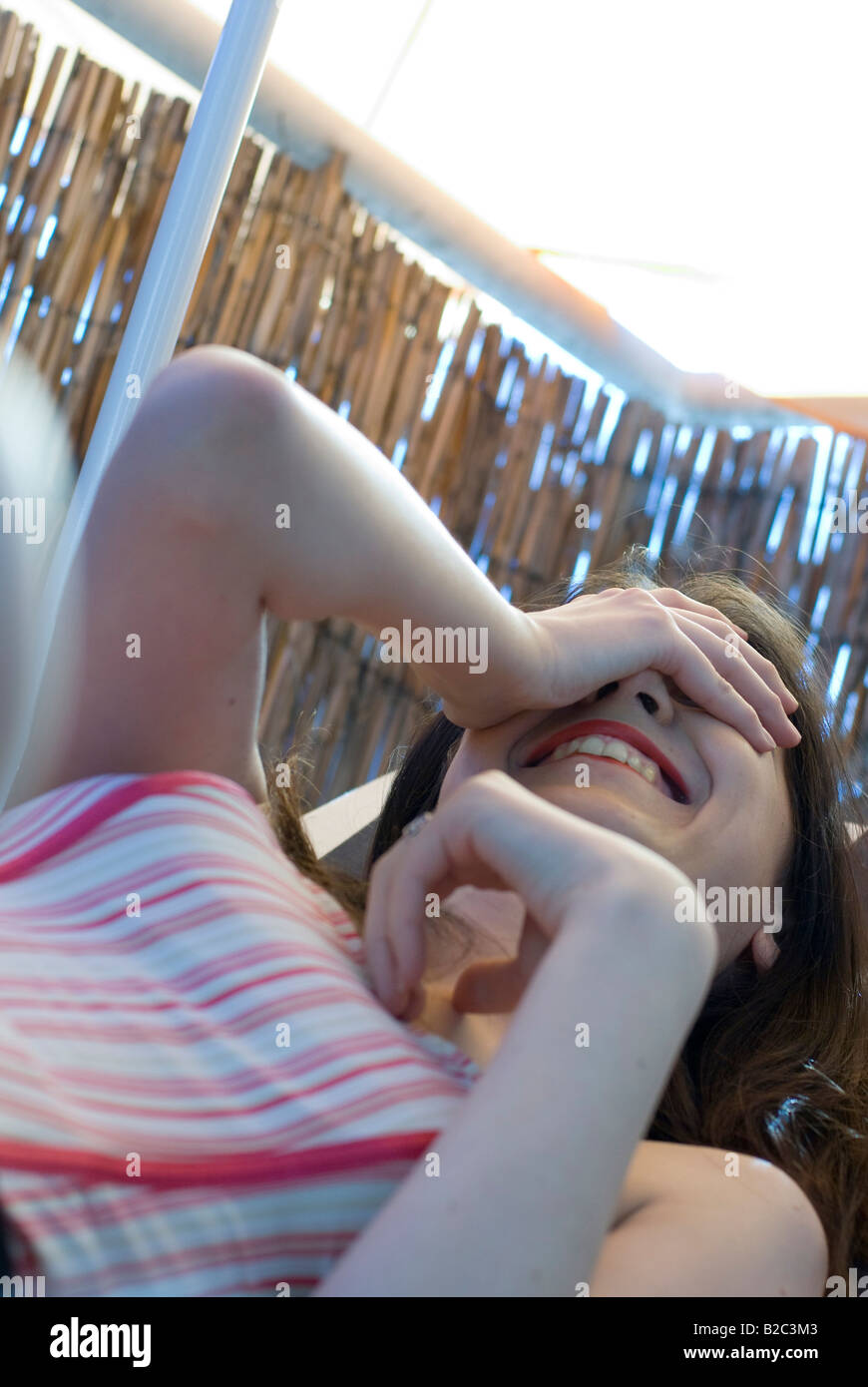 Attraente dai capelli scuri donna ridere con la sua mano che copre gli occhi Foto Stock