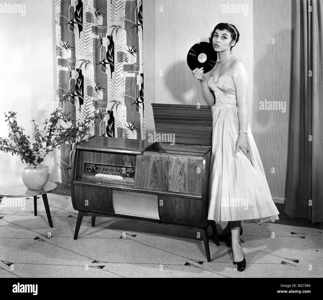 La donna posa vicino a un record giocatore, foto storiche da circa 1955 Foto Stock