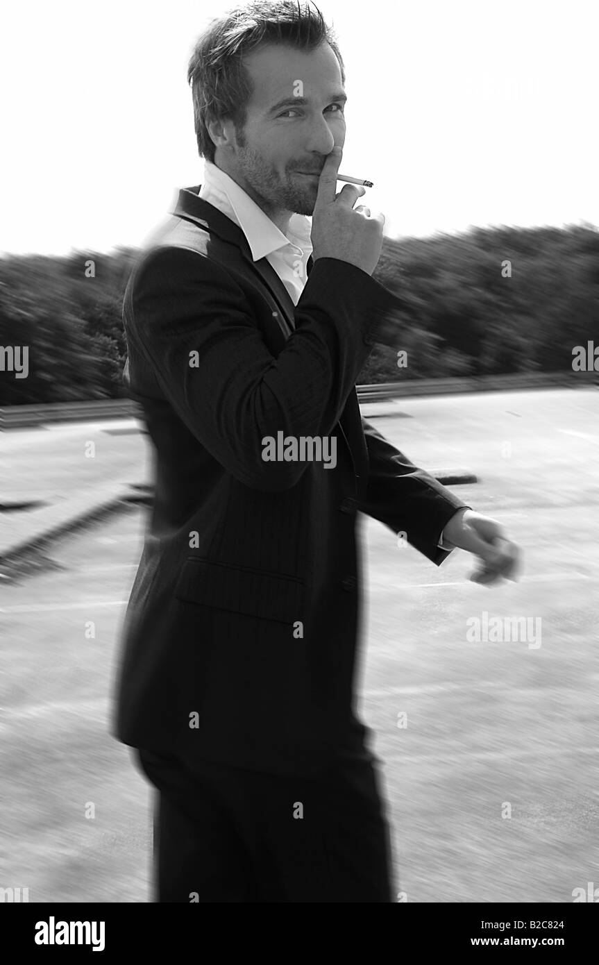 Il 33-anno-vecchio uomo indossa una tuta, fumatori Foto Stock